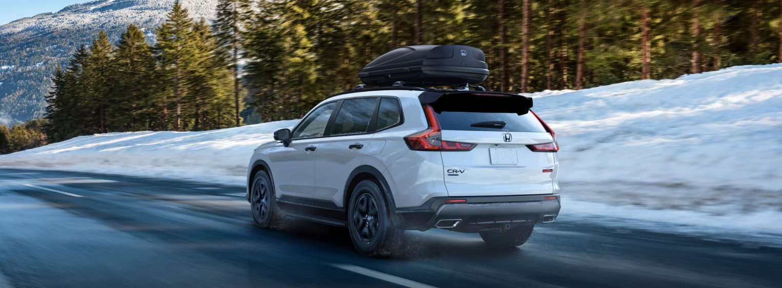 2026 Honda CR-V white driving in winter on a snowy road in Quebec.