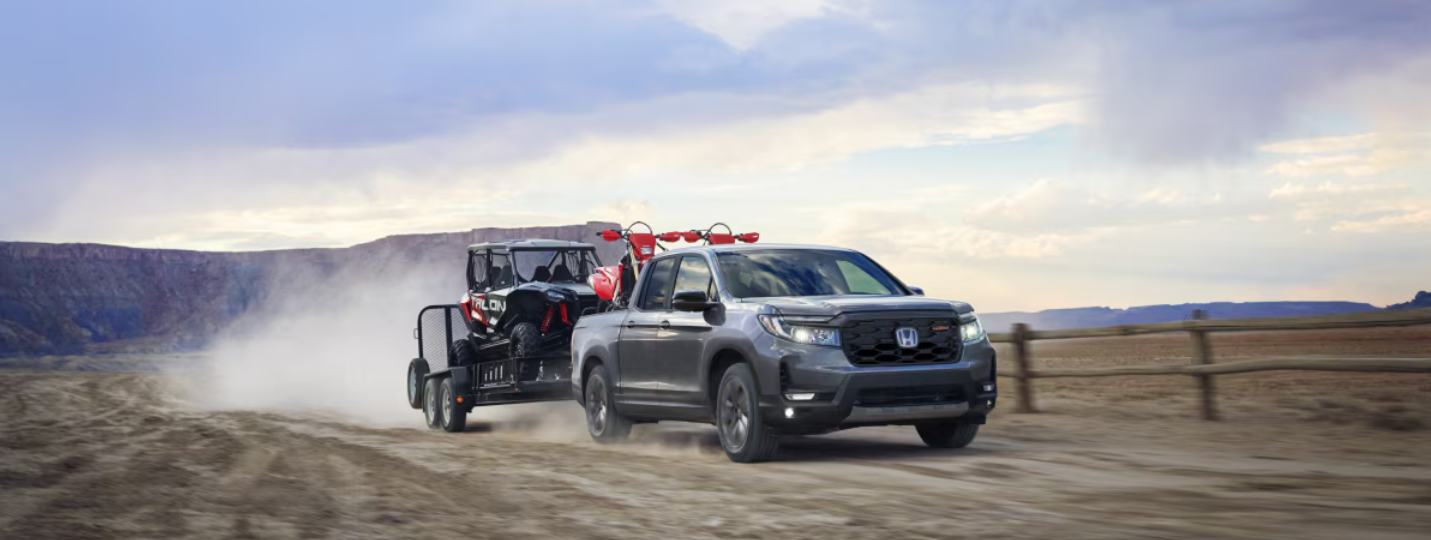 Honda Ridgeline towing a trailer with off-road vehicles, ready for rugged spring adventures